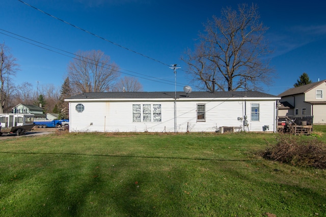 rear view of house featuring a lawn and cooling unit