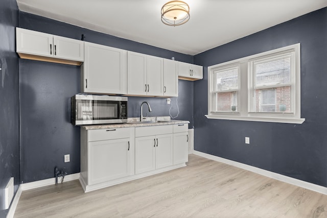 kitchen with white cabinets, light wood-type flooring, and sink