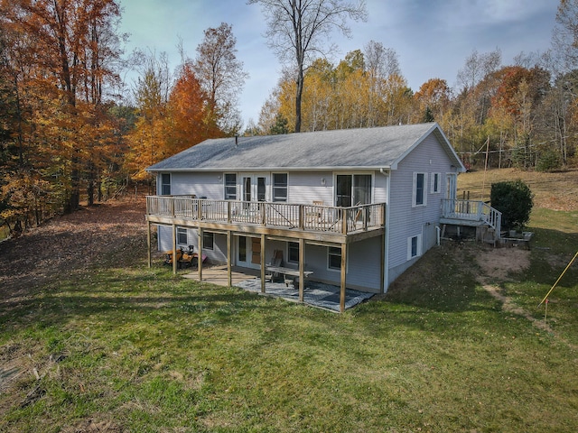 rear view of property featuring a yard, a patio, and a wooden deck