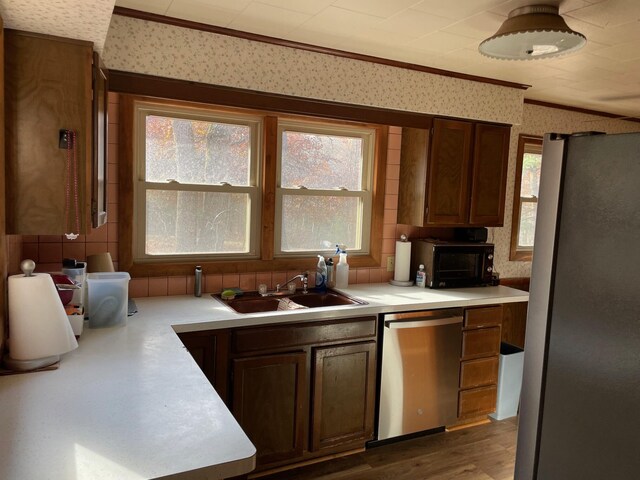 7468 W 6 1/2 Mile Rd, Irons, MI 49644 - kitchen featuring appliances with stainless steel finishes, a sink, ornamental molding, wallpapered walls, and light countertops