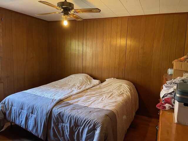 7468 W 6 1/2 Mile Rd, Irons, MI 49644 - bedroom with wood finished floors, wooden walls, and ceiling fan