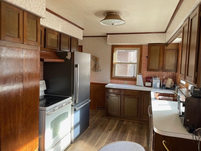 7468 W 6 1/2 Mile Rd, Irons, MI 49644 - kitchen featuring white electric stove, wallpapered walls, wainscoting, dark wood-type flooring, and under cabinet range hood
