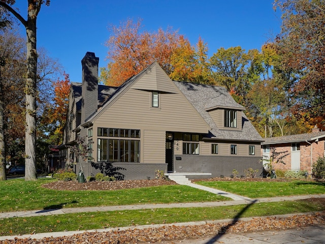 view of front of home with a front lawn, brick siding, and roof with shingles