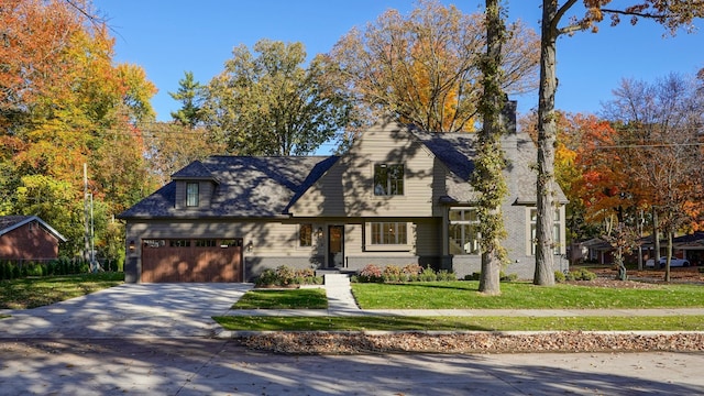 cape cod-style house with brick siding, driveway, a front yard, and an attached garage