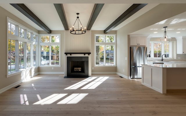 unfurnished living room with a notable chandelier, visible vents, a large fireplace, and beam ceiling