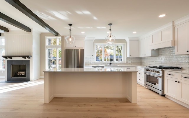 kitchen with a kitchen island, appliances with stainless steel finishes, light wood-style flooring, and white cabinetry