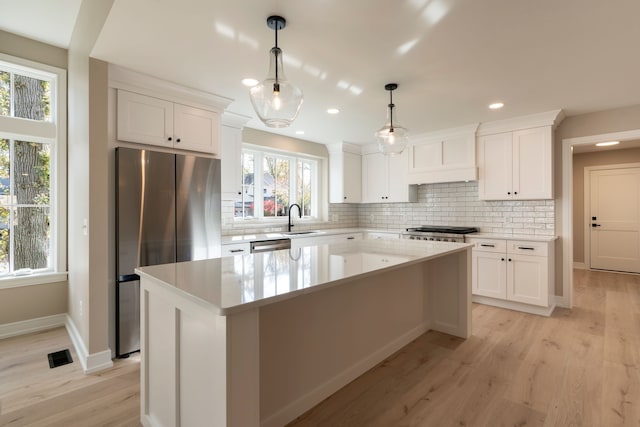 kitchen with visible vents, a sink, a kitchen island, white cabinetry, and appliances with stainless steel finishes