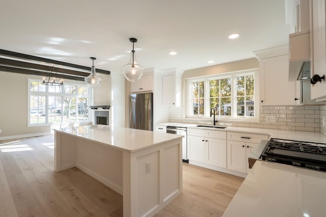 kitchen featuring a sink, tasteful backsplash, a kitchen island, stainless steel appliances, and light wood finished floors