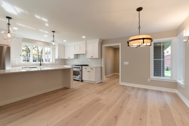 kitchen with refrigerator, high end stove, light countertops, white cabinetry, and tasteful backsplash