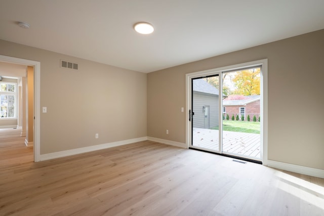 unfurnished room with light wood-type flooring, visible vents, and baseboards