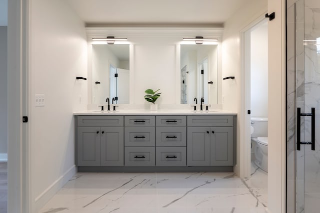 bathroom featuring a sink, toilet, marble finish floor, and double vanity