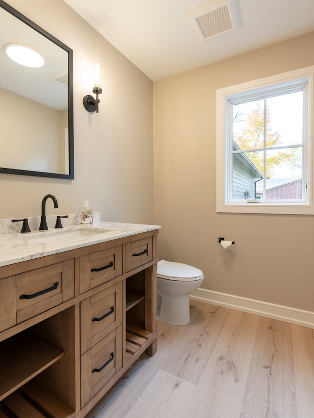 bathroom featuring vanity, wood finished floors, visible vents, baseboards, and toilet