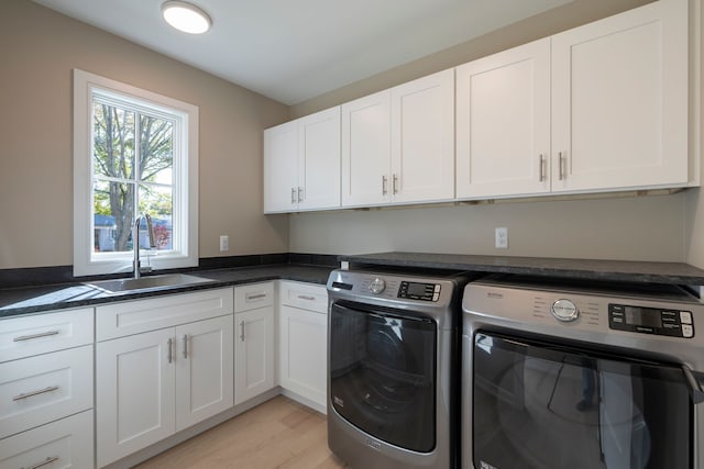 clothes washing area featuring light wood-type flooring, cabinet space, independent washer and dryer, and a sink