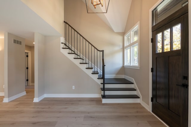 entrance foyer featuring visible vents, baseboards, light wood-style flooring, and stairs