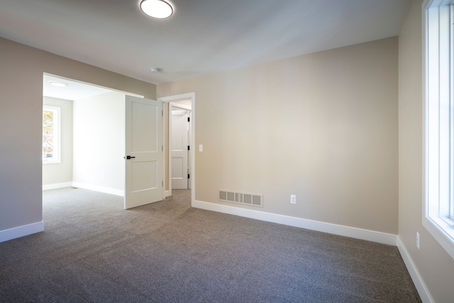 carpeted empty room featuring visible vents and baseboards