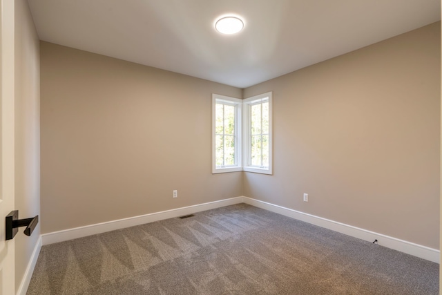 carpeted spare room with visible vents and baseboards