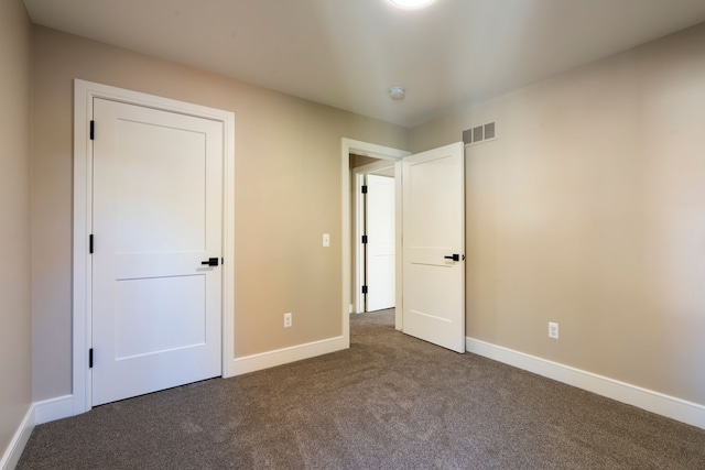 unfurnished bedroom with visible vents, baseboards, and dark carpet