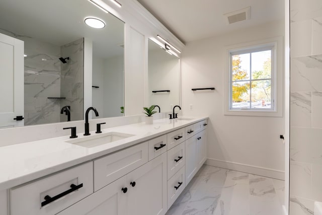 bathroom with double vanity, baseboards, marble finish floor, and a sink