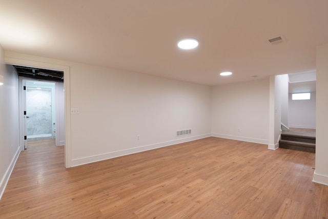 empty room with baseboards, visible vents, light wood finished floors, recessed lighting, and stairs