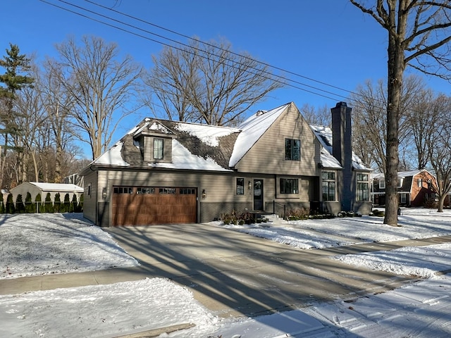 view of front of home featuring driveway, a chimney, and a garage