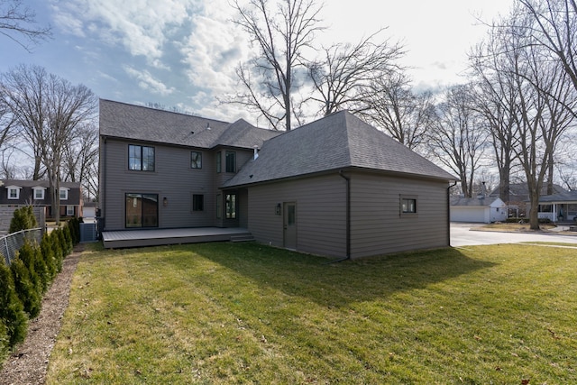 back of house with a wooden deck, roof with shingles, a yard, and fence