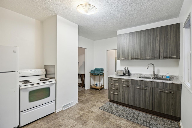 kitchen featuring a textured ceiling, dark brown cabinets, white appliances, and sink