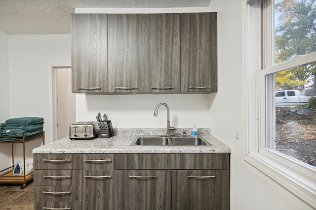 kitchen featuring dark brown cabinets, sink, and a textured ceiling