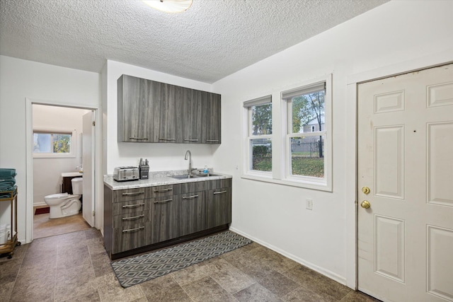 kitchen with a textured ceiling, dark brown cabinets, and sink