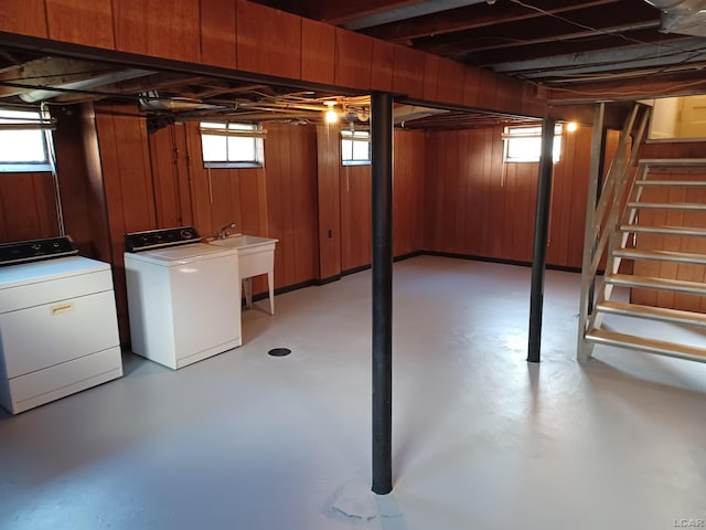 basement featuring separate washer and dryer, wooden walls, and sink