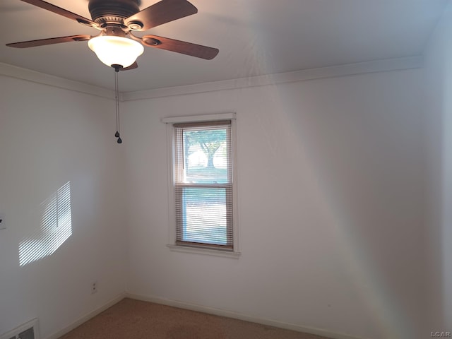 carpeted spare room with ceiling fan and ornamental molding