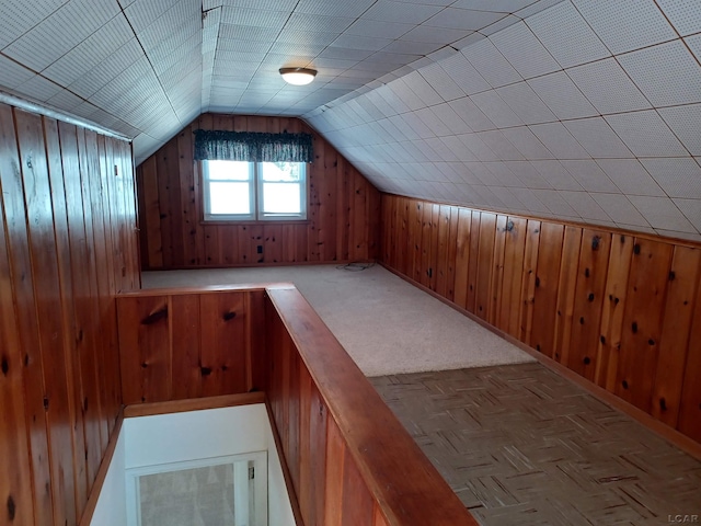 bonus room with wood walls, vaulted ceiling, and light parquet floors