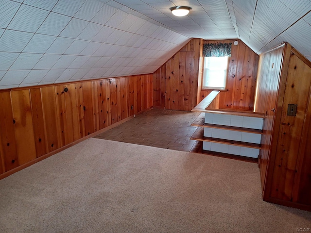 additional living space with wood walls, light carpet, and lofted ceiling