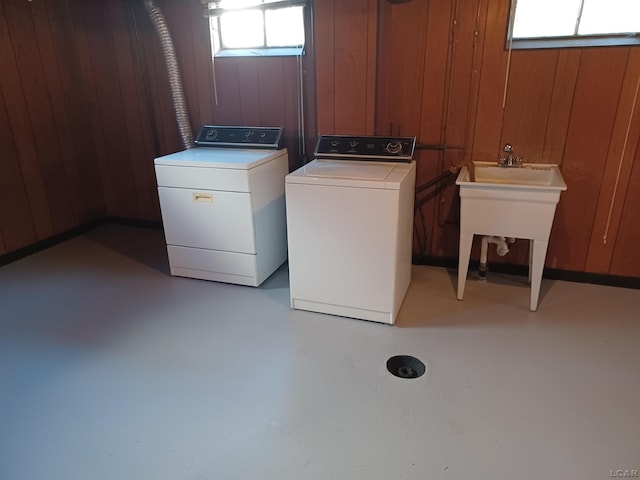 washroom with washing machine and dryer, a wealth of natural light, and wood walls