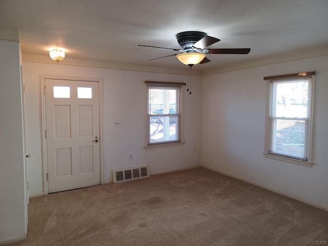 foyer entrance with ceiling fan, plenty of natural light, and light colored carpet