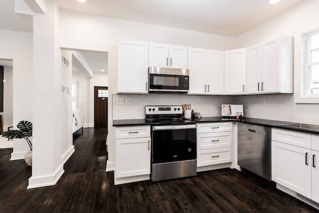 kitchen with white cabinets, appliances with stainless steel finishes, dark hardwood / wood-style flooring, and plenty of natural light