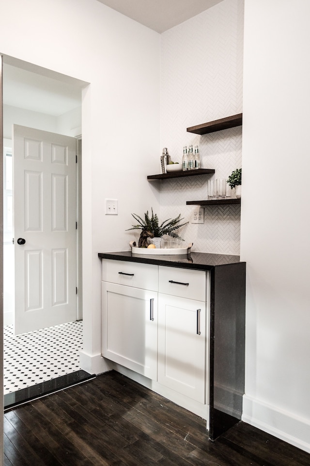 bar featuring white cabinetry and dark hardwood / wood-style flooring