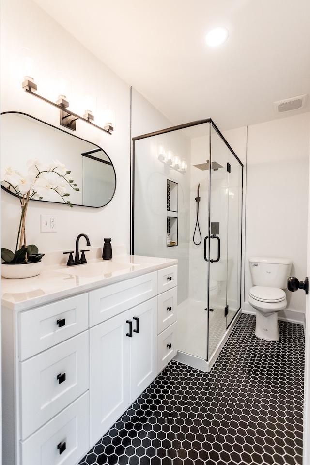 bathroom featuring toilet, a shower with shower door, and vanity