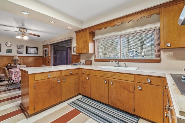 kitchen with ceiling fan, kitchen peninsula, sink, and wooden walls