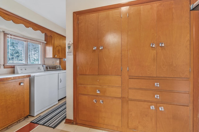 laundry room featuring washing machine and clothes dryer, light tile patterned floors, and cabinets