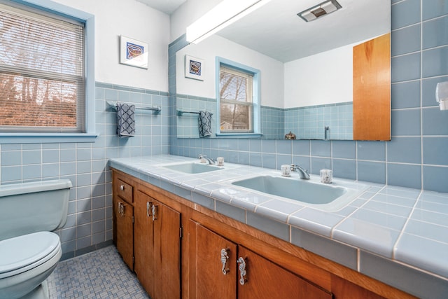 bathroom with tile patterned flooring, vanity, toilet, and tile walls