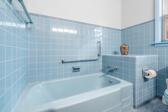 bathroom with tile patterned flooring, a bathtub, tile walls, and toilet