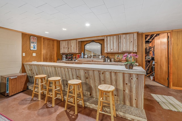 kitchen with kitchen peninsula, radiator heating unit, a breakfast bar area, and wood walls