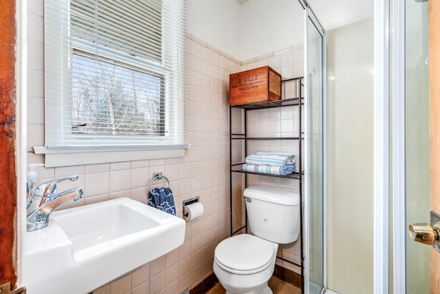 bathroom with toilet, sink, tile walls, and walk in shower