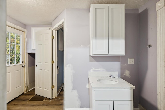 bathroom with hardwood / wood-style floors, vanity, and a textured ceiling