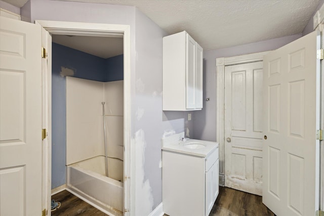 washroom with a textured ceiling, sink, and dark hardwood / wood-style floors