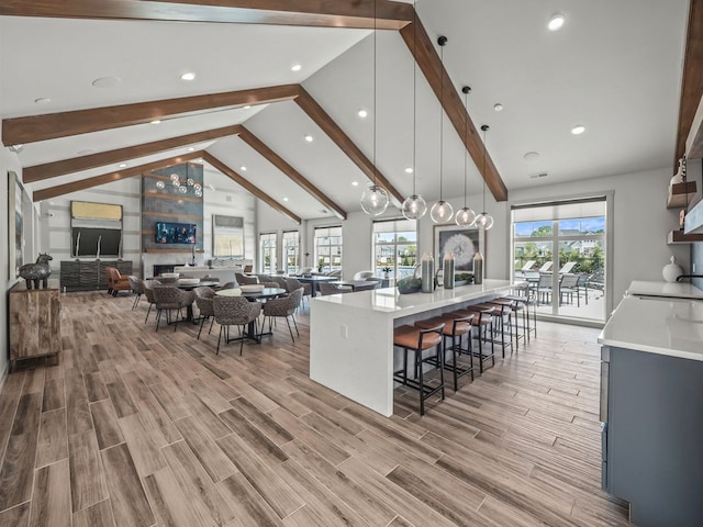 kitchen featuring a breakfast bar, a spacious island, beam ceiling, decorative light fixtures, and high vaulted ceiling