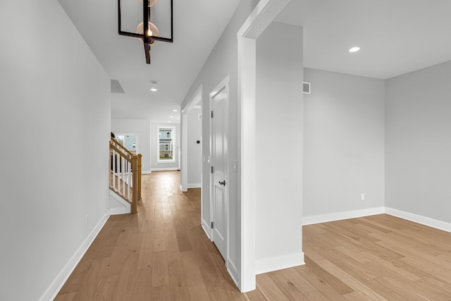 hallway with light hardwood / wood-style flooring and a notable chandelier