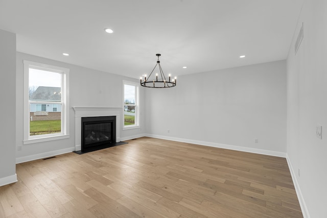 unfurnished living room featuring light hardwood / wood-style flooring and an inviting chandelier