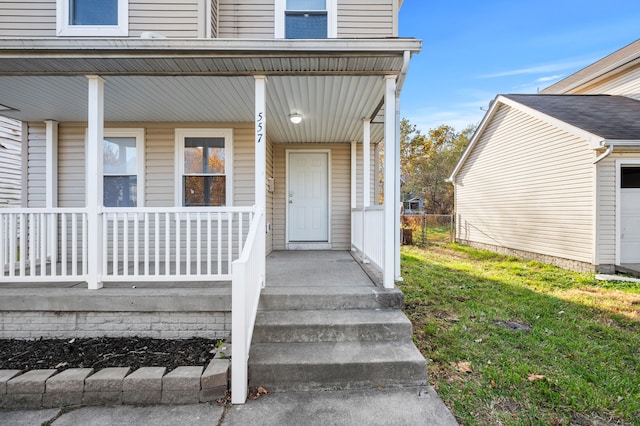 view of exterior entry featuring a lawn and covered porch