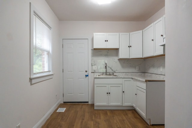 kitchen with tasteful backsplash, white cabinetry, sink, and dark hardwood / wood-style floors